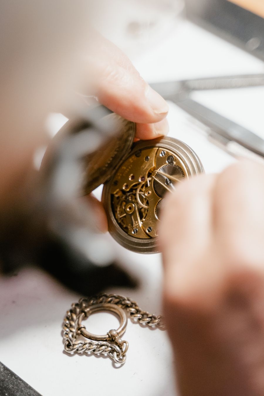 Hands opening a pocket watch case to check the movement